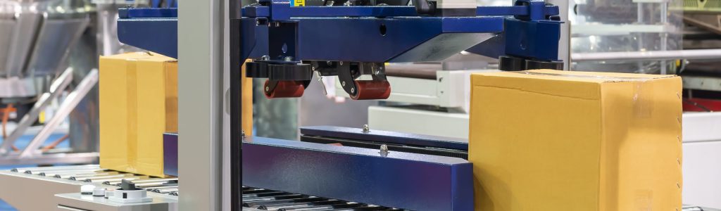 Depositphotos_615349376_XL paper cardboard box or carton on roller conveyor of automatic masking tape sealing machine for commercial packing industrial